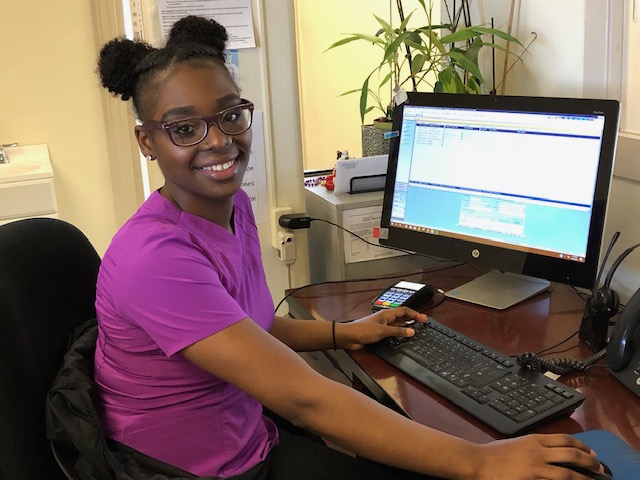 Staff member in pink scrubs at the reception computer